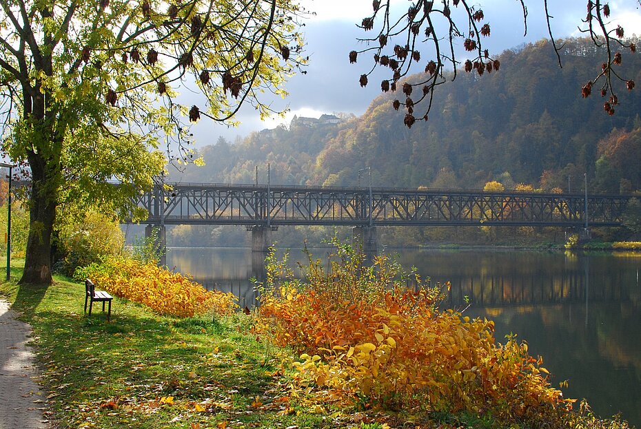 Doppelstockbrücke zwischen Bullay und Alf im Herbst, Uferweg mit Bank an der Mosel